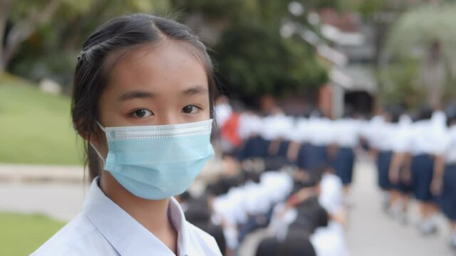 Slow motion of Asian female high school student in white uniform is wearing a mask during the Coronavirus 2019 (Covid-19) epidemic.