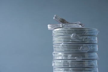 Stack of plates and cutlery wrapped in plastic