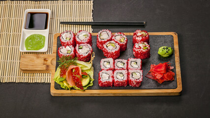 Food banner. Sushi roll with salmon meat with rice in red flying fish caviar. Pickled ginger, spicy...