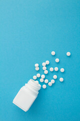 Top view of white bottle with the white pills on the blue  background. Copy space.