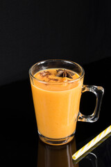 Drink with pumpkin and cinnamon in the glass cup on the dark background