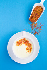 Top view of saffron latte or saffron moon milk in the white cup on the blue background with copy space