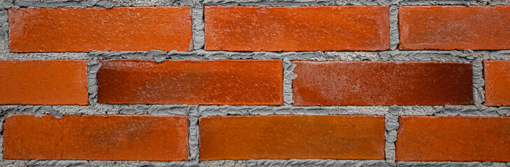 Fototapeta na wymiar The old wall was built of orange-red mud bricks with a rustic shabby texture. brickwork with gray cement mortar. Banner background