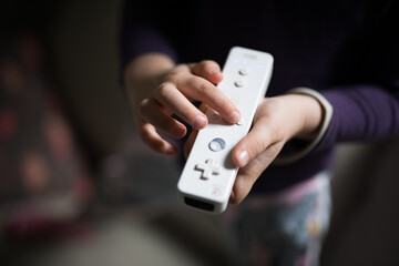 A small child girl dressed in pink holding a gaming consolte controller remote in her lounge room at home playing an active game to keep entertained and fit 
