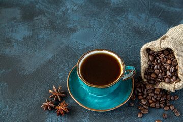 Cup of coffee, coffee beans and star anise on the background of a dark table. Still life. Top view with copy space.