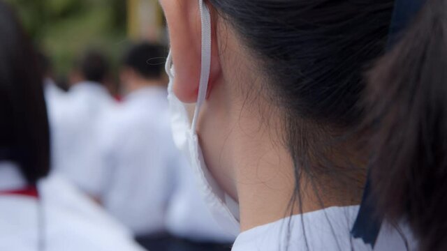 Slow motion of Asian female high school student in white uniform is wearing a mask and standing in row during the Coronavirus 2019 (Covid-19) epidemic.
