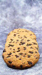 Soft, freshly baked chocolate chip cookies on a gray marble kitchen countertop. American traditional sweet pastry pastry, delicious homemade dessert. Culinary background. Vertical photography