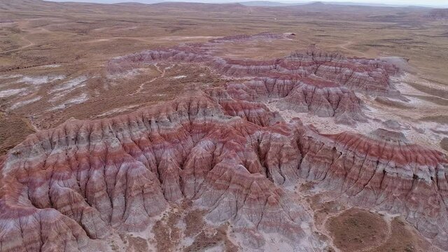 Aerial view of textured red desert in Wyoming flying down towards the hills viewing patters of the earth below in mars like landscape.