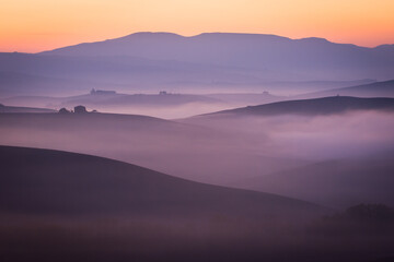 Fototapeta na wymiar foggy valley in purple and orange colors, autumn early morning, italy, tuscany