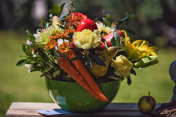 Pot with fruits, vegetables and flowers in the field on a green background.