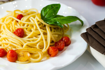 Pasta spaghetti with tomatoes and garlic served with basil leaves