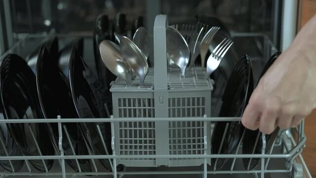 Open dishwasher with clean dishes. A open open a dishwash machine in the kitchen. A concept of a modern help in the kitchen.