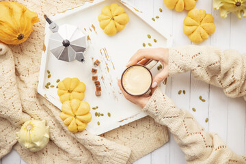 Autumn mood, warm cup of hot coffee warming in hands of woman by window top view
