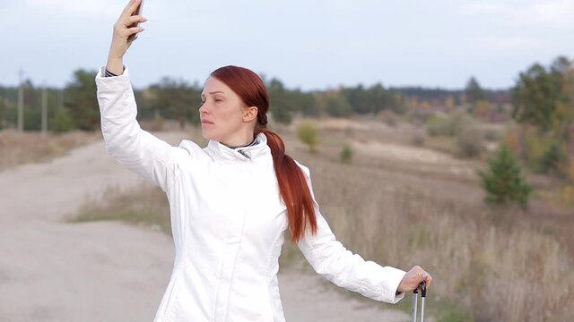 a lonely woman with a suitcase is walking on an empty road without a cellular connection, trying to catch a phone signal
