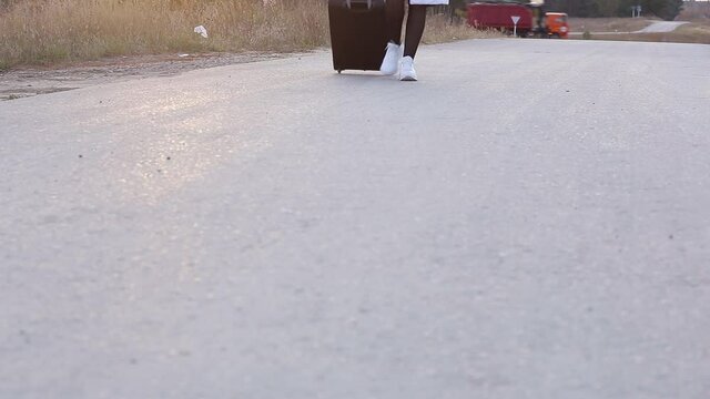 a lonely woman with a suitcase is walking on an empty road, the concept of travel, to be in an unknown place alone