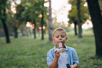 little boy blowing soap balloons in city park