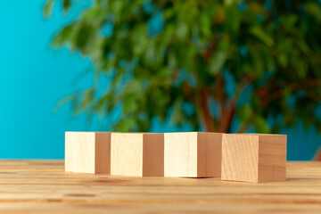 Wooden blocks on desk against blurred plant background