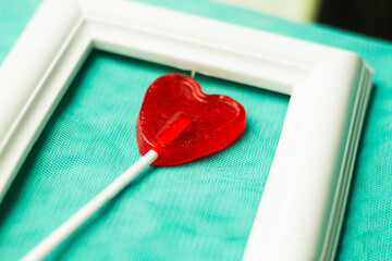 Piruleta con forma de corazón de color rojo con marco blanco.