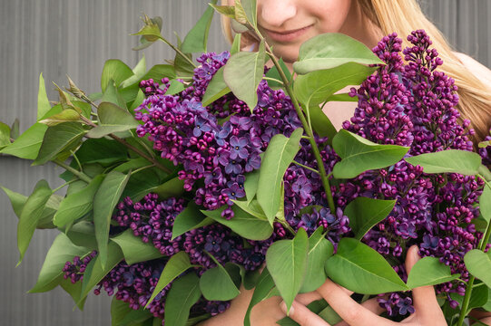 Young Girl Holding Purple Lilac Bouquet Looking Down and Smiling