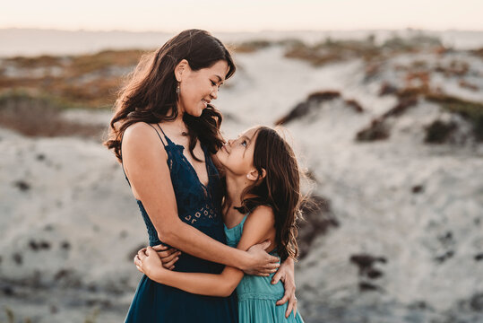 Happy mother hugging 8 yr old daughter at the beach