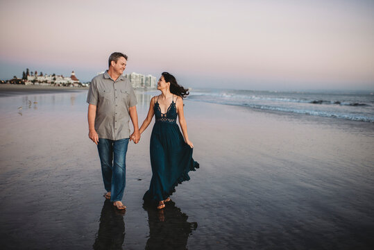 Happy mid-40's couple gazing at each other while walking on the beach