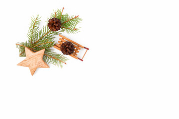 Christmas background of fir twigs, wooden zero waste home decoration: sleigh, cone, and star