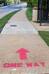Spray painted one way direction sign on a sidewalk to manage social distancing in Annapolis, MD....
