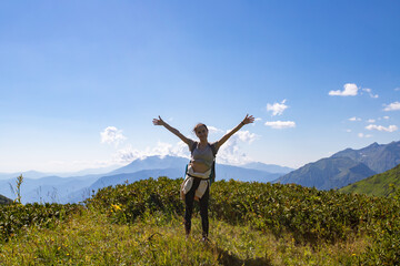 Fototapeta premium A girl stands on top of a mountain hands up, freedom, happiness concept