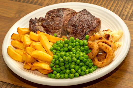 Steak Dinner - Rump Steak, With Chips, Peas Onion Rings And Cauliflower Cheese.