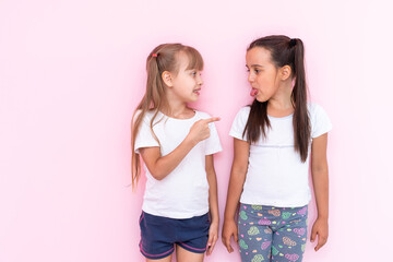 Image of two angry teenage girls with braids in casual clothes standing isolated over pink...