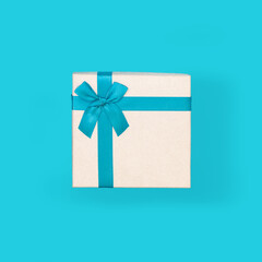 white gift box with a blue ribbon and bow, on a blue background. Top view, close-up. Idea - layout for design, template.