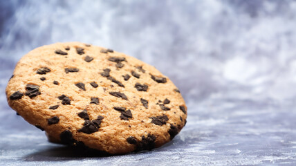 Fototapeta na wymiar One soft, freshly baked chocolate chip cookie on a gray marble kitchen countertop. American traditional dessert. Delicious sweet food. Homemade baking concept for the holiday. Culinary background