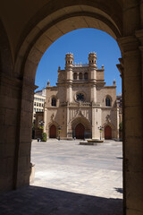 Fototapeta na wymiar Main square of Castellon de la Plana through an arch with the Co-Cathedral of Santa Maria in the background on a sunny day with a blue sky, Spain