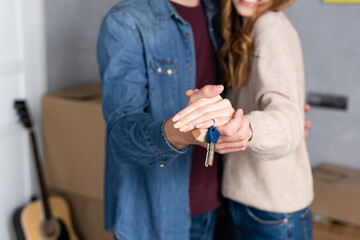 cropped view of man and woman holding hands and keys, moving concept