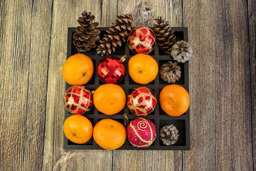 Christmas composition with tangerines, gift boxes, cones on a dark wooden background. Top view with copy space.