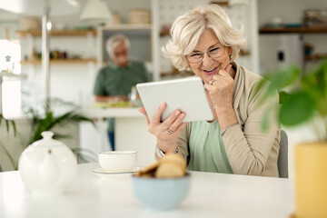 Happy mature woman using digital tablet at home.