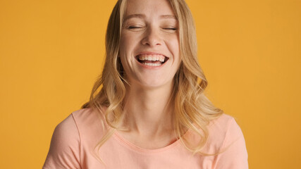 Attractive girl laughing at something funny isolated on yellow b