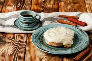 Glazed cinnabon bun in green plate on wooden table