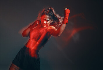 Cool female fighter in boxing bandages trains in studio in red neon light. Mixed martial arts. Long exposure shot - obrazy, fototapety, plakaty