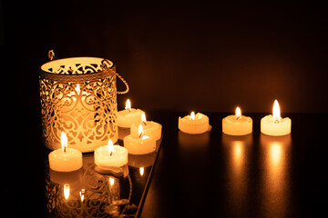 Intrincate metal candle holder with a lighting scented candle are displayed on the blak stone table in the dark living room of the house. Selective focus