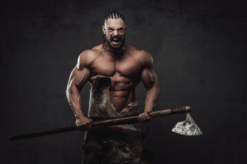 Furious and angry nord warrior with muscular build and dreadlocks posing crying while holding axe...