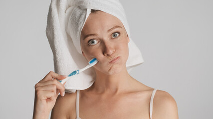 Portrait of girl with towel on head and toothbrush thoughtfully