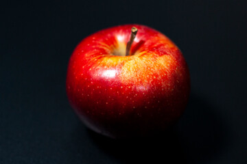 Red Apple on a dark background. The fresh stalk is turned towards the lens.