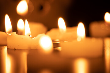 Close up of burning candles on the wooden table with blurred Christmas candles background. Selective focus.