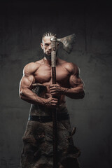 Brutal and powerful viking warrior with dreadlocks and beard posing with axe which covers half of...