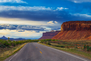 The road passing through the prairie against the backdrop of a mountain landscape.