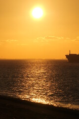 a beautiful sunset at the westerschelde sea with an orange sky above the black water and the nose of a ship at the right