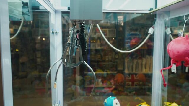 Moving forceps of the claw crane machine. Successful attempt to grab a toy. Promotional games as opportunities for consumers to win a prize through luck or skill that are designed to promote product.