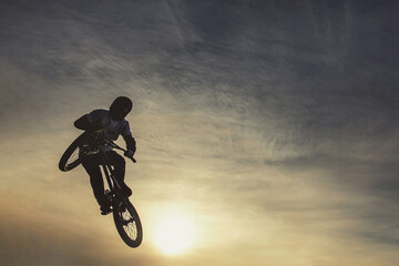 Unrecognizable biker performing acrobatic jump at sunny sky - Guy riding bmx bicycle at extreme...