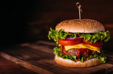 Home made fresh tasty burger with lettuce and cheese on wooden rustic table.